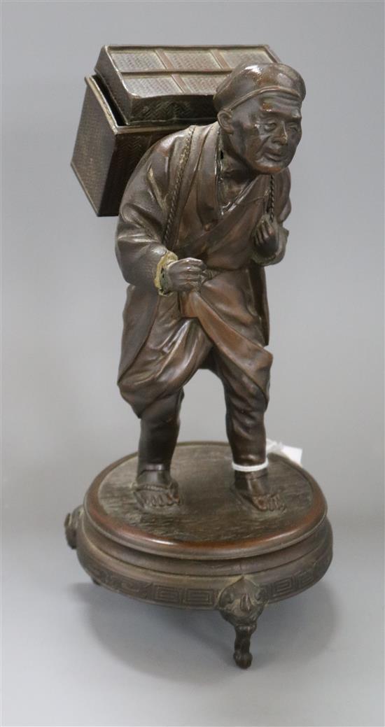 A Japanese spelter group of an elderly man carrying a large chest height 28cm